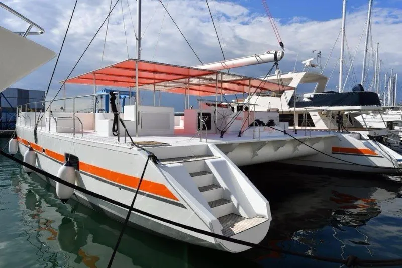  Yacht Photos Pics Custom DAYCHARTER 2026 catamaran with orange accents docked at marina under blue sky.