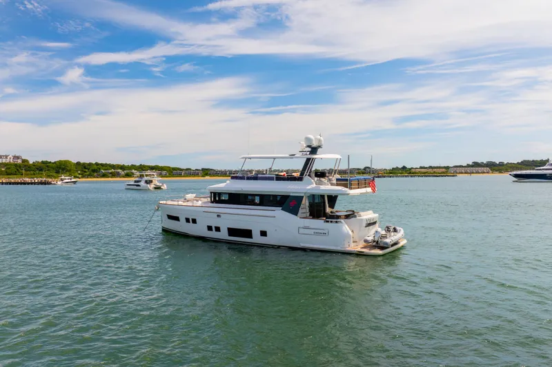 Amor Fati Yacht Photos Pics 2019 Sirena 64 yacht cruising in a scenic coastal area under a clear blue sky.