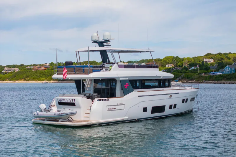 Amor Fati Yacht Photos Pics 2019 Sirena 64 yacht on calm water near a scenic shoreline.