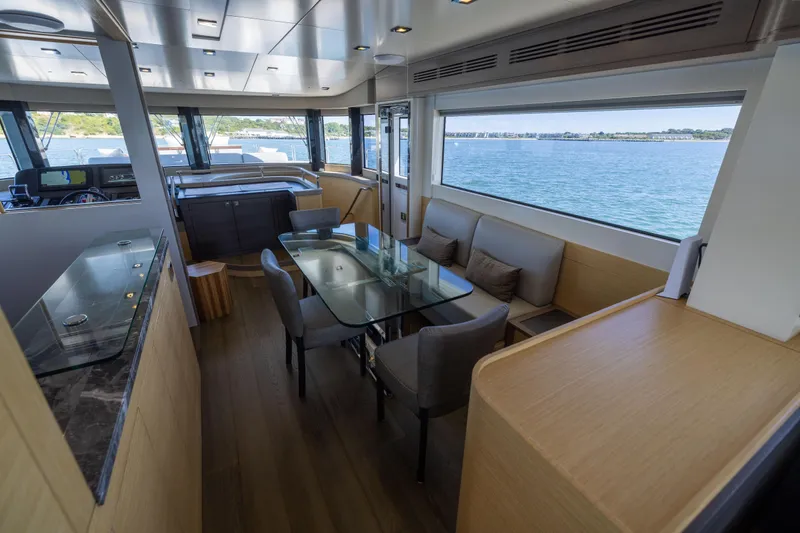 Amor Fati Yacht Photos Pics Luxurious interior of 2019 Sirena 64 yacht with glass dining table and panoramic windows.