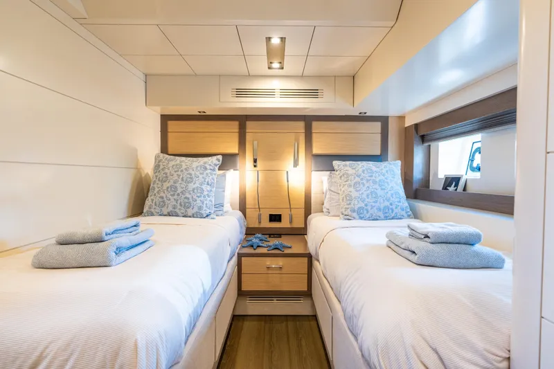Amor Fati Yacht Photos Pics Luxurious twin cabin interior on 2019 Sirena 64 yacht, featuring elegant bedding and modern design.