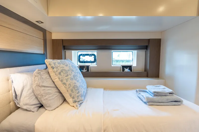 Amor Fati Yacht Photos Pics Luxurious cabin interior of 2019 Sirena 64 yacht with cozy bedding and window view.
