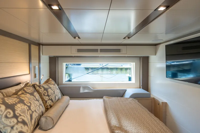 Amor Fati Yacht Photos Pics Luxurious interior of 2019 Sirena 64 yacht with elegant bedding and large window view.