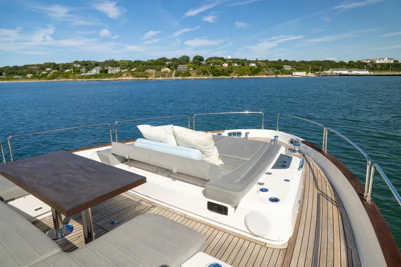 Amor Fati Yacht Photos Pics Luxurious 2019 Sirena 64 yacht deck with sun loungers and table, overlooking serene coastal waters.