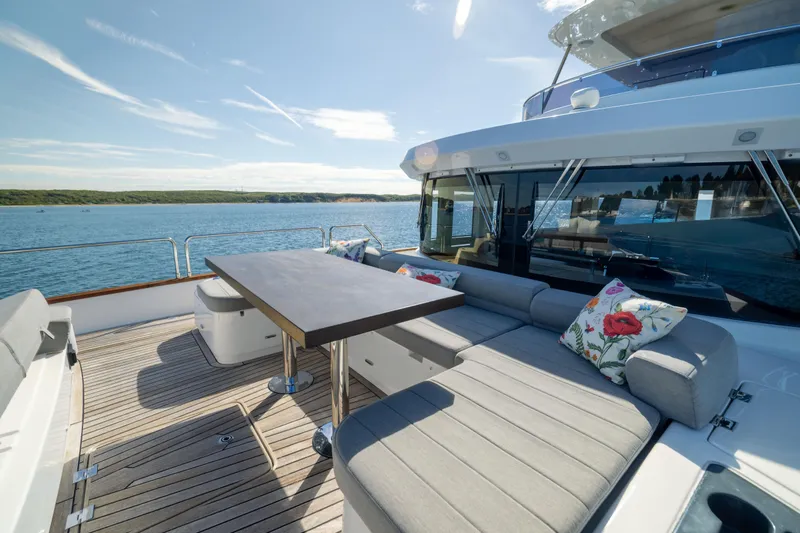 Amor Fati Yacht Photos Pics Luxurious 2019 Sirena 64 yacht deck with seating, table, and scenic ocean view.