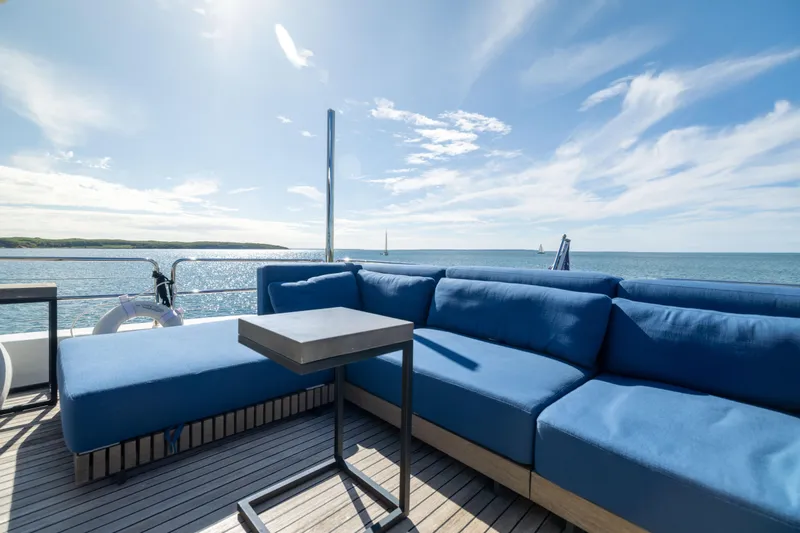 Amor Fati Yacht Photos Pics Luxurious Sirena 64 yacht deck with blue seating, ocean view, and sunny sky, 2019 model.