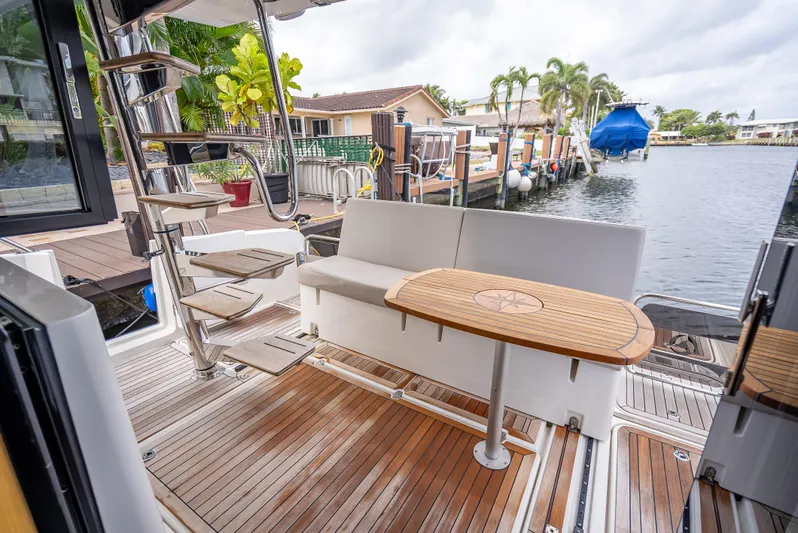  Yacht Photos Pics Luxurious 2021 Skamander Monaco yacht deck with seating and table, overlooking a serene waterfront.