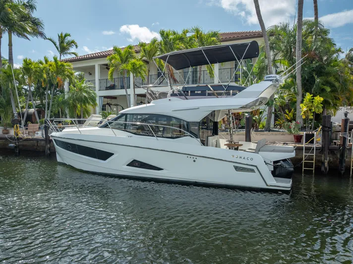  Yacht Photos Pics 2021 Skamander Monaco yacht docked by a waterfront home with palm trees.