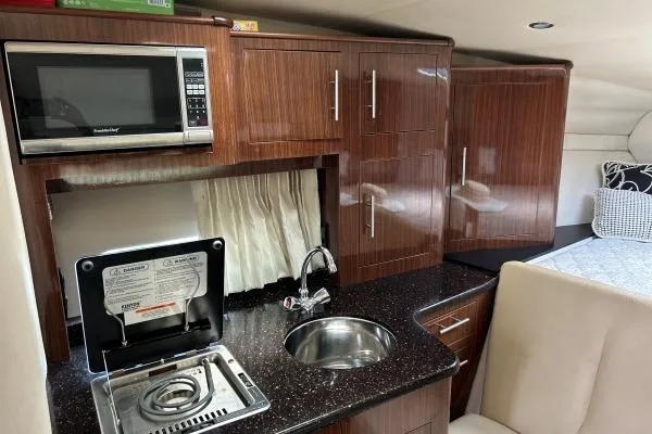 Qtech-1 Yacht Photos Pics 2015 Regal 32 Express yacht interior with kitchenette, featuring microwave, stove, and sink.