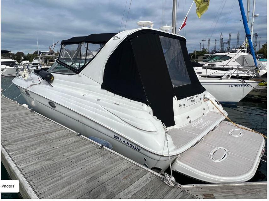 2004 Larson 370 boat docked at marina, featuring sleek design and black canopy.