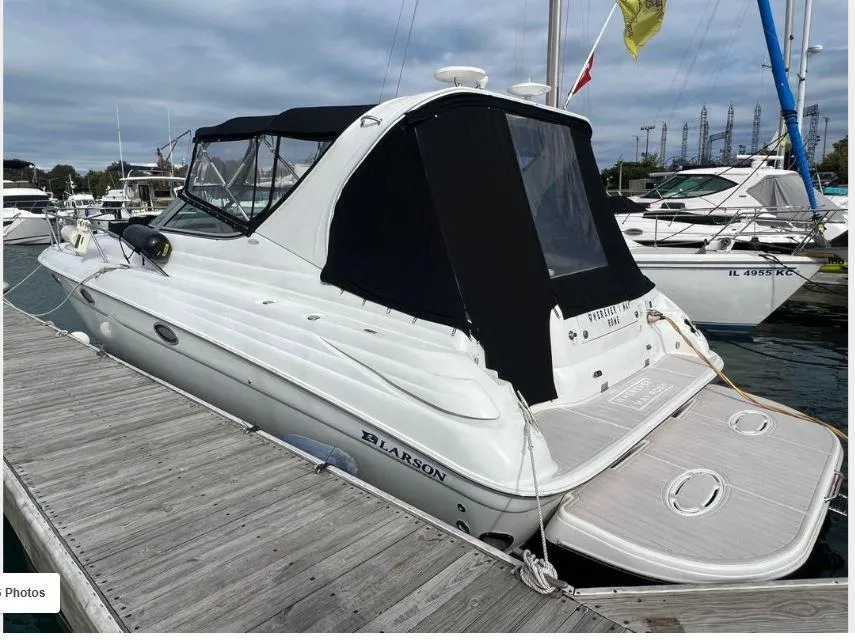 2004 Larson 370 boat docked at marina, featuring sleek design and black canopy.