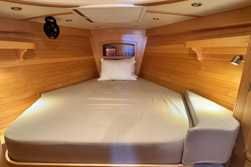 Munequita Yacht Photos Pics Cozy wooden cabin interior of 2013 Tartan 4000 sailboat with bed and shelves.