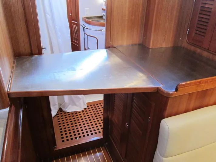 Solitude Yacht Photos Pics Wooden interior of a 2018 Passport 545 yacht with a foldable table and cabinetry.