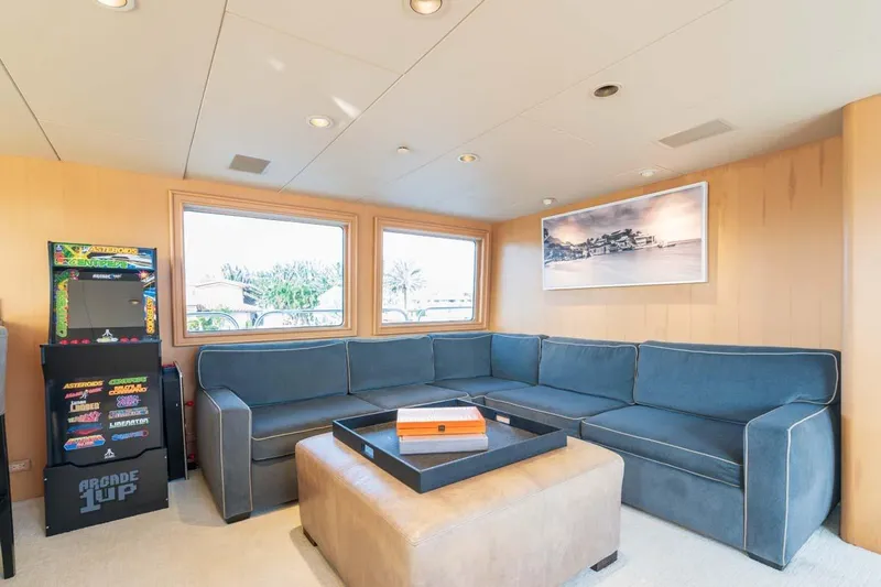 Chanson Yacht Photos Pics Luxurious yacht interior with blue sectional sofa, arcade machine, and scenic artwork. Christensen Tri-Deck 1995.