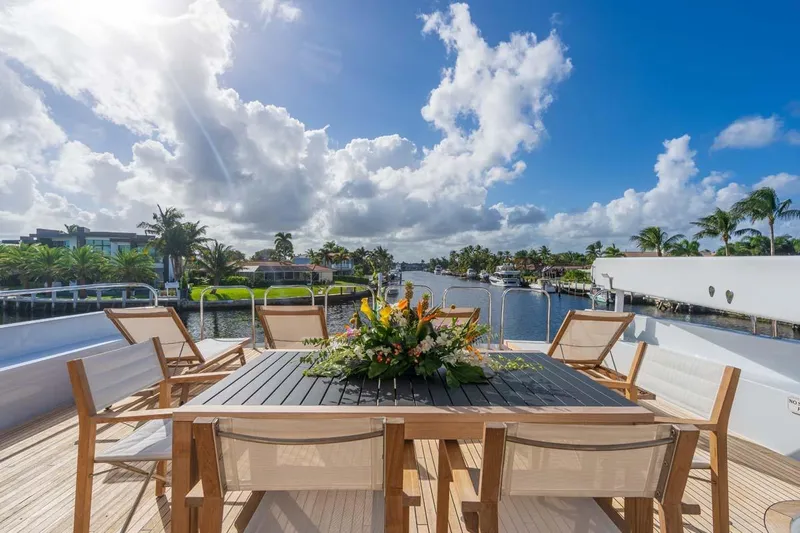 Chanson Yacht Photos Pics Luxurious 1995 Christensen Tri-Deck yacht deck with elegant outdoor dining setup, scenic waterfront view.