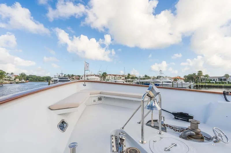 Chanson Yacht Photos Pics Christensen Tri-Deck 1995 yacht deck with bell, docked in a scenic marina.