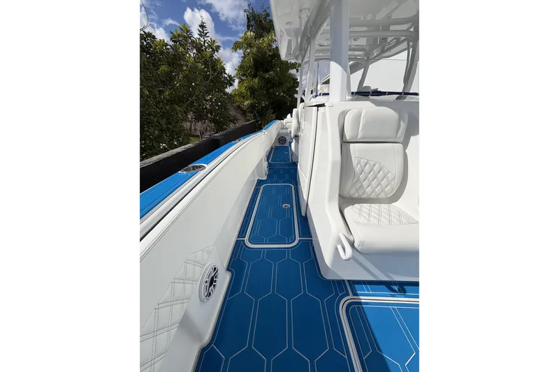  Yacht Photos Pics 2012 Deep Impact 399 Sport boat with blue deck and white seating, surrounded by greenery.