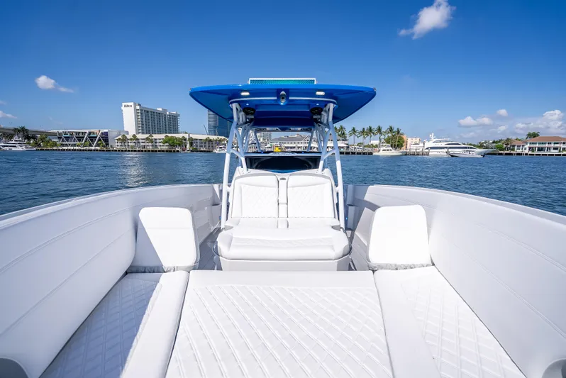  Yacht Photos Pics 2025 Nor-Tech 340 Sport boat with white seating, blue canopy, and scenic waterfront view.
