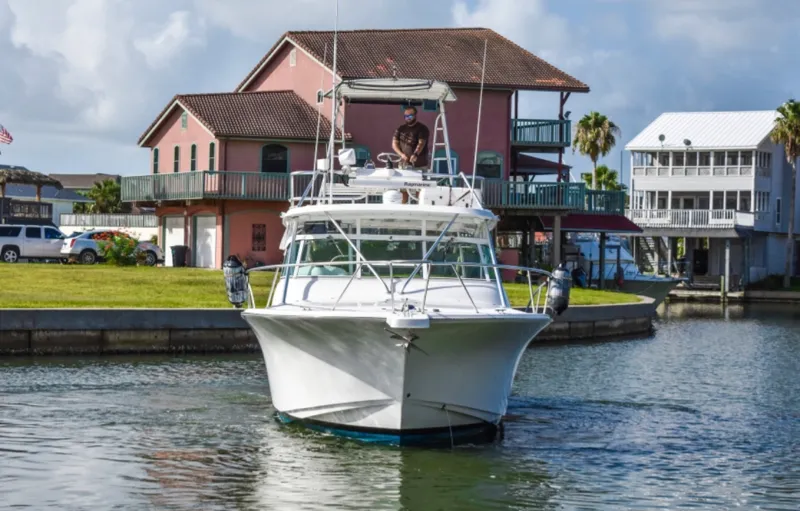 Rocky N Friends Yacht Photos Pics 2003 Luhrs 36 Open boat navigating a canal near waterfront homes.