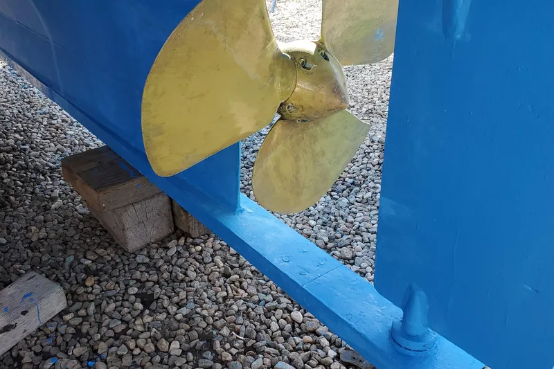 Nantucket Sleighride Yacht Photos Pics Propeller of 2005 Custom Sea Raider Catamaran on gravel, blue hull visible.