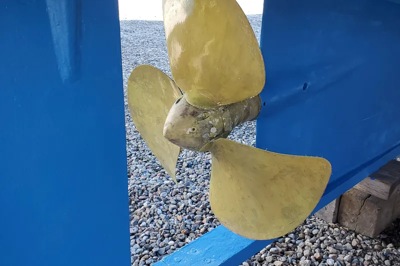 Nantucket Sleighride Yacht Photos Pics Propeller of 2005 Custom Sea Raider Catamaran on gravel, blue hull background.