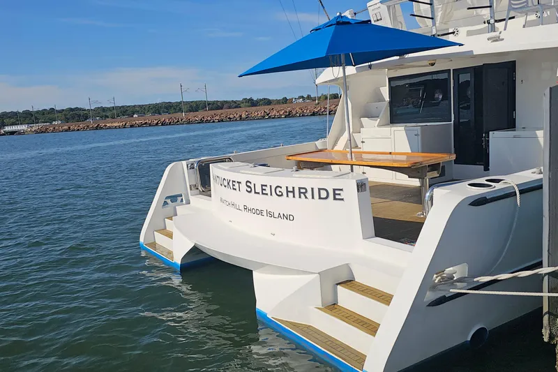 Nantucket Sleighride Yacht Photos Pics Custom 2005 Sea Raider Catamaran docked, featuring a blue umbrella and wooden deck.