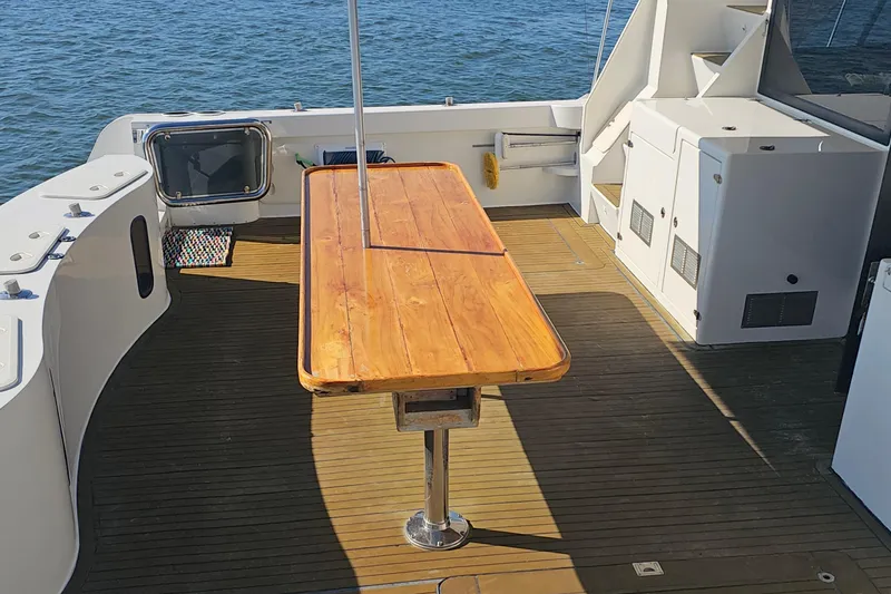 Nantucket Sleighride Yacht Photos Pics Custom 2005 Sea Raider Catamaran deck with wooden table, overlooking the ocean.