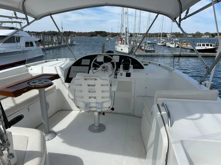 Tryst Yacht Photos Pics 2006 Beneteau 42 Swift Trawler helm with marina view, featuring white seating and navigation equipment.