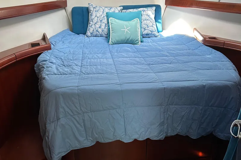 Tryst Yacht Photos Pics Cozy cabin bed in 2006 Beneteau 42 Swift Trawler with blue bedding and decorative pillows.