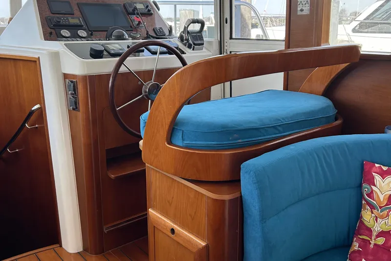 Tryst Yacht Photos Pics Interior helm of 2006 Beneteau 42 Swift Trawler with blue cushioned seat and wooden accents.