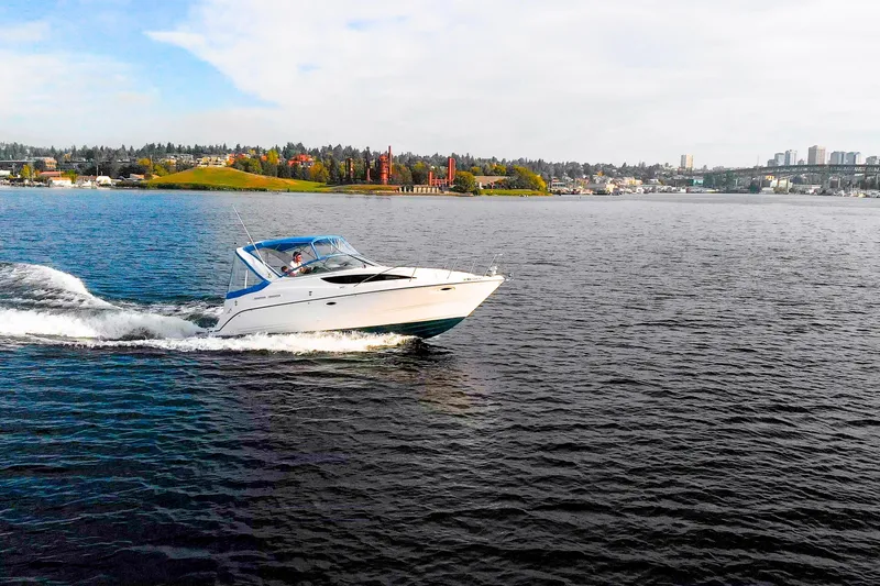 No Name - Our Trade Yacht Photos Pics 2005 Bayliner 285 cruising on a scenic lake with city skyline in the background.