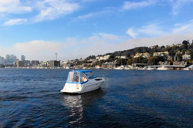No Name - Our Trade Yacht Photos Pics 2005 Bayliner 285 cruising on a scenic urban waterfront with city skyline in the background.