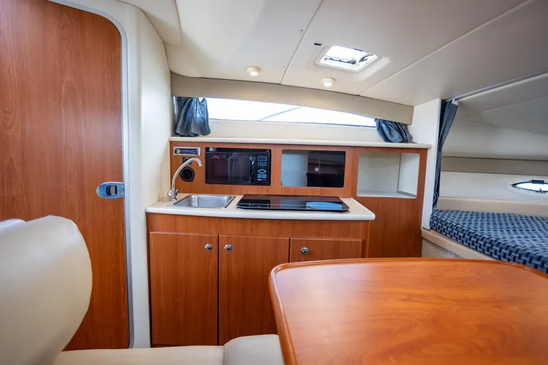 No Name - Our Trade Yacht Photos Pics Interior of a 2005 Bayliner 285 boat featuring a kitchenette and seating area.