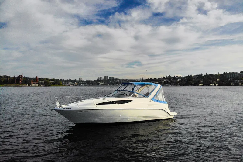 No Name - Our Trade Yacht Photos Pics 2005 Bayliner 285 boat on calm water with cityscape background under cloudy sky.