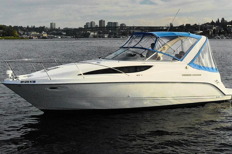No Name - Our Trade Yacht Photos Pics 2005 Bayliner 285 boat with blue canopy on a calm lake, city skyline in background.