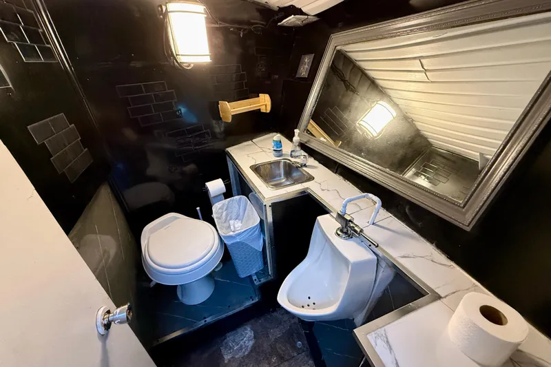 Island Princess Yacht Photos Pics Compact bathroom with toilet, urinal, sink, and large mirror in a 1983 Custom Steel Passenger model.