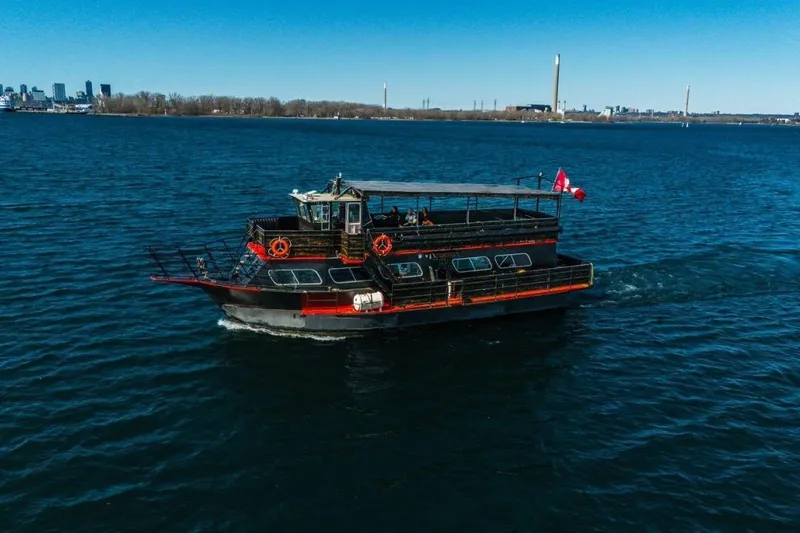 Island Princess Yacht Photos Pics Custom Steel Passenger boat, 1983 model, cruising on a clear blue lake with city skyline.
