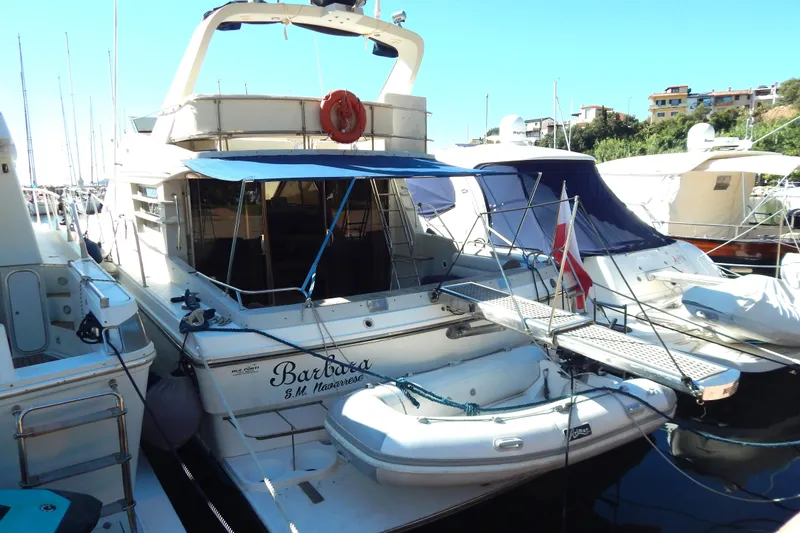  Yacht Photos Pics 1992 Fairline 50 yacht docked with inflatable boat, featuring blue canopy and white hull.