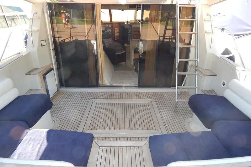  Yacht Photos Pics 1992 Fairline 50 yacht interior with wooden deck, blue cushioned seating, and ladder access.