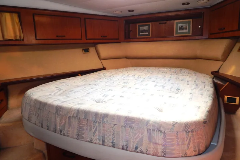  Yacht Photos Pics Cozy bedroom interior of 1992 Fairline 50 yacht with wood cabinets and patterned bedding.