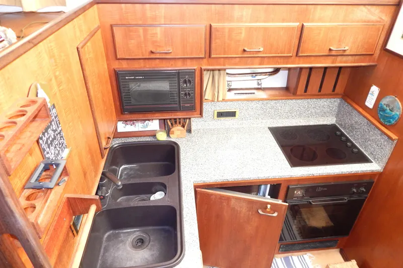 Yacht Photos Pics 1992 Fairline 50 yacht kitchen with wooden cabinets, dual sink, microwave, and electric stove.