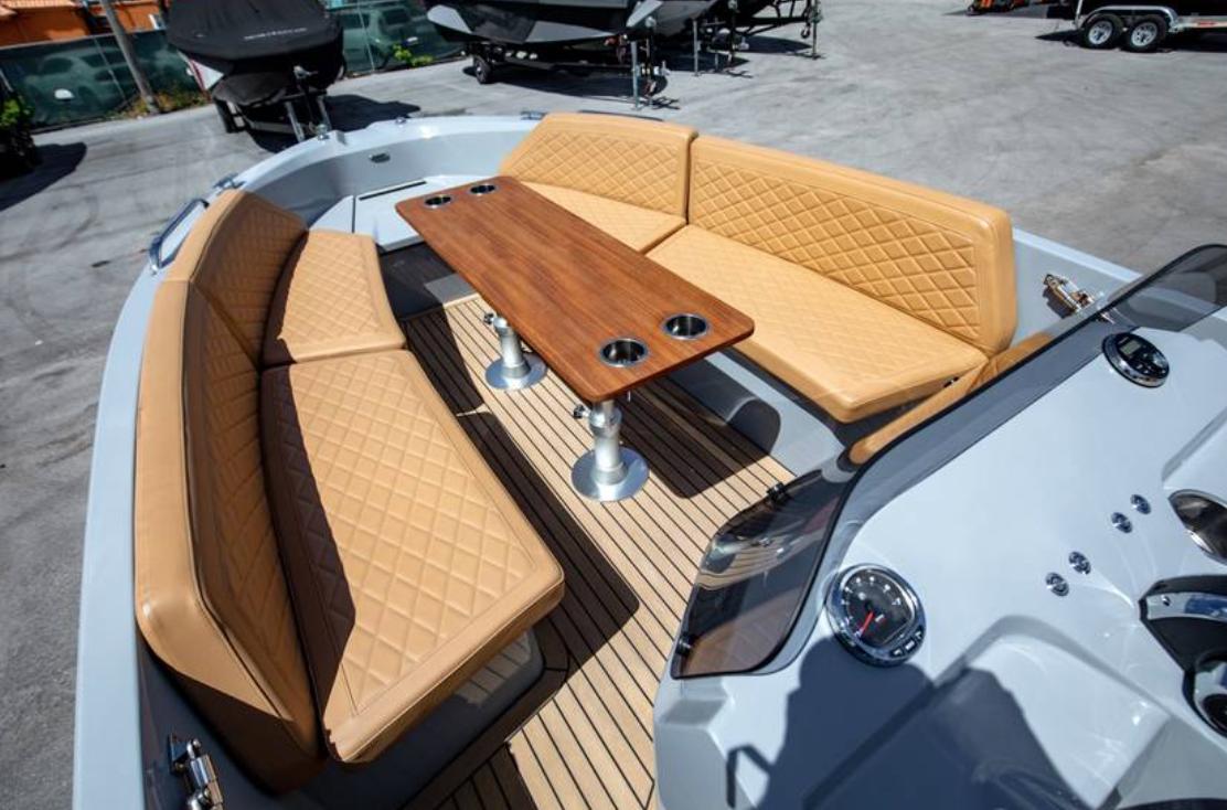 2022 Rand BREEZE boat interior with tan quilted seating and wooden table.