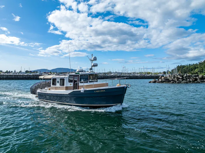 Caldonia Yacht Photos Pics 2013 Ranger Tugs R 29 cruising in a scenic harbor under a partly cloudy sky.