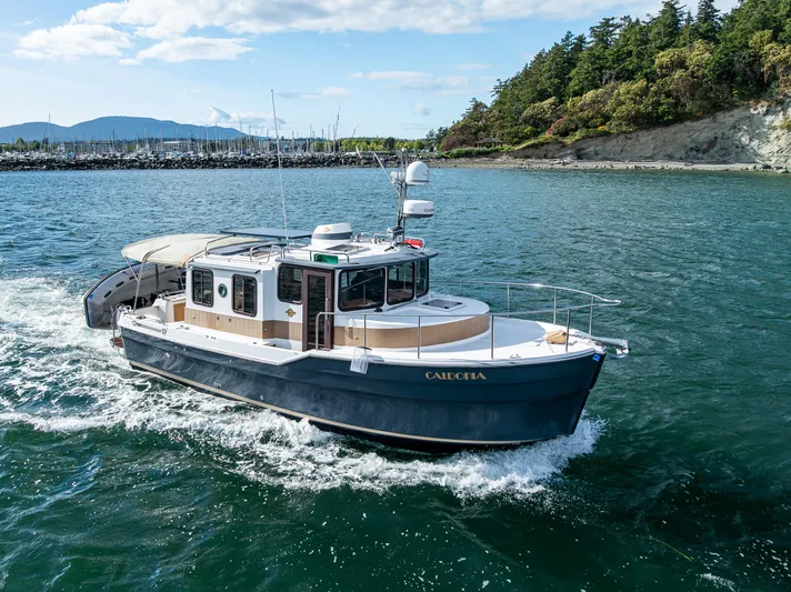 Caldonia Yacht Photos Pics 2013 Ranger Tugs R 29 cruising on scenic coastal waters with lush greenery.