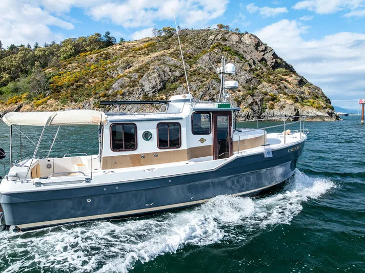 Caldonia Yacht Photos Pics 2013 Ranger Tugs R 29 cruising near rocky coastline under blue sky.