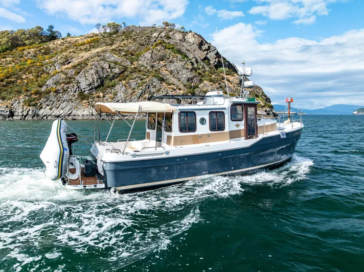 Caldonia Yacht Photos Pics 2013 Ranger Tugs R 29 cruising near rocky island under blue sky.