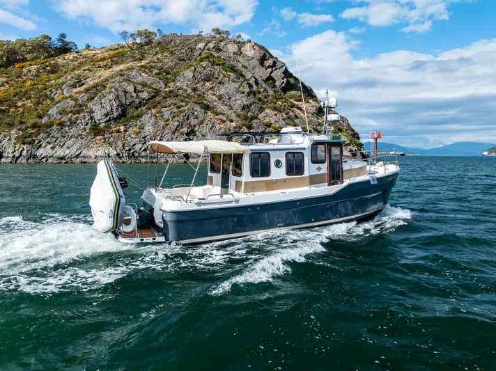 Caldonia Yacht Photos Pics 2013 Ranger Tugs R 29 cruising near rocky coastline under blue sky.