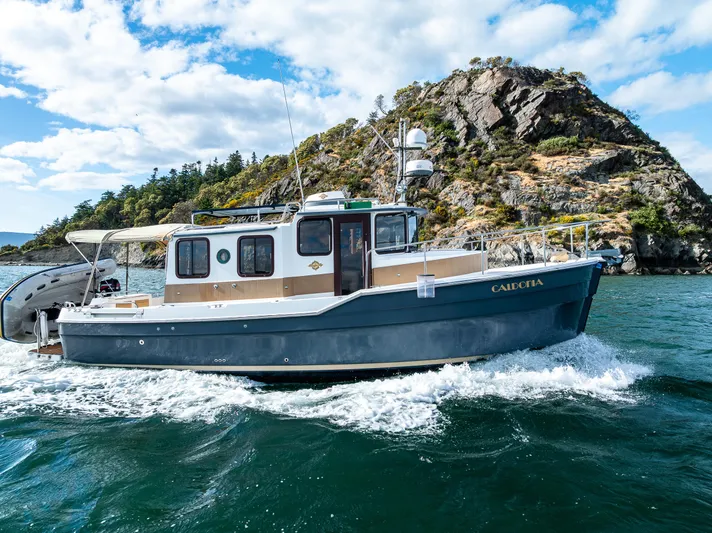 Caldonia Yacht Photos Pics 2013 Ranger Tugs R 29 cruising near rocky island under blue sky.