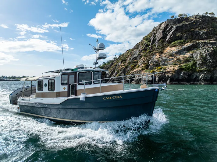 Caldonia Yacht Photos Pics 2013 Ranger Tugs R 29 cruising near rocky coastline under blue sky.