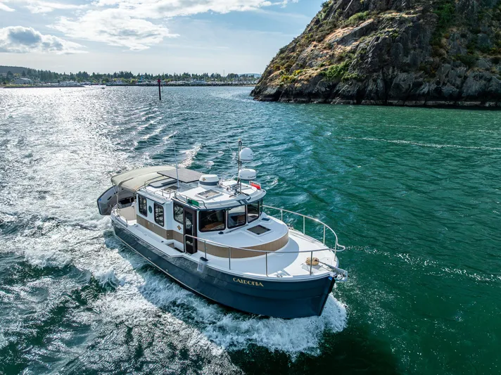 Caldonia Yacht Photos Pics 2013 Ranger Tugs R 29 cruising on scenic waterway near rocky shoreline.